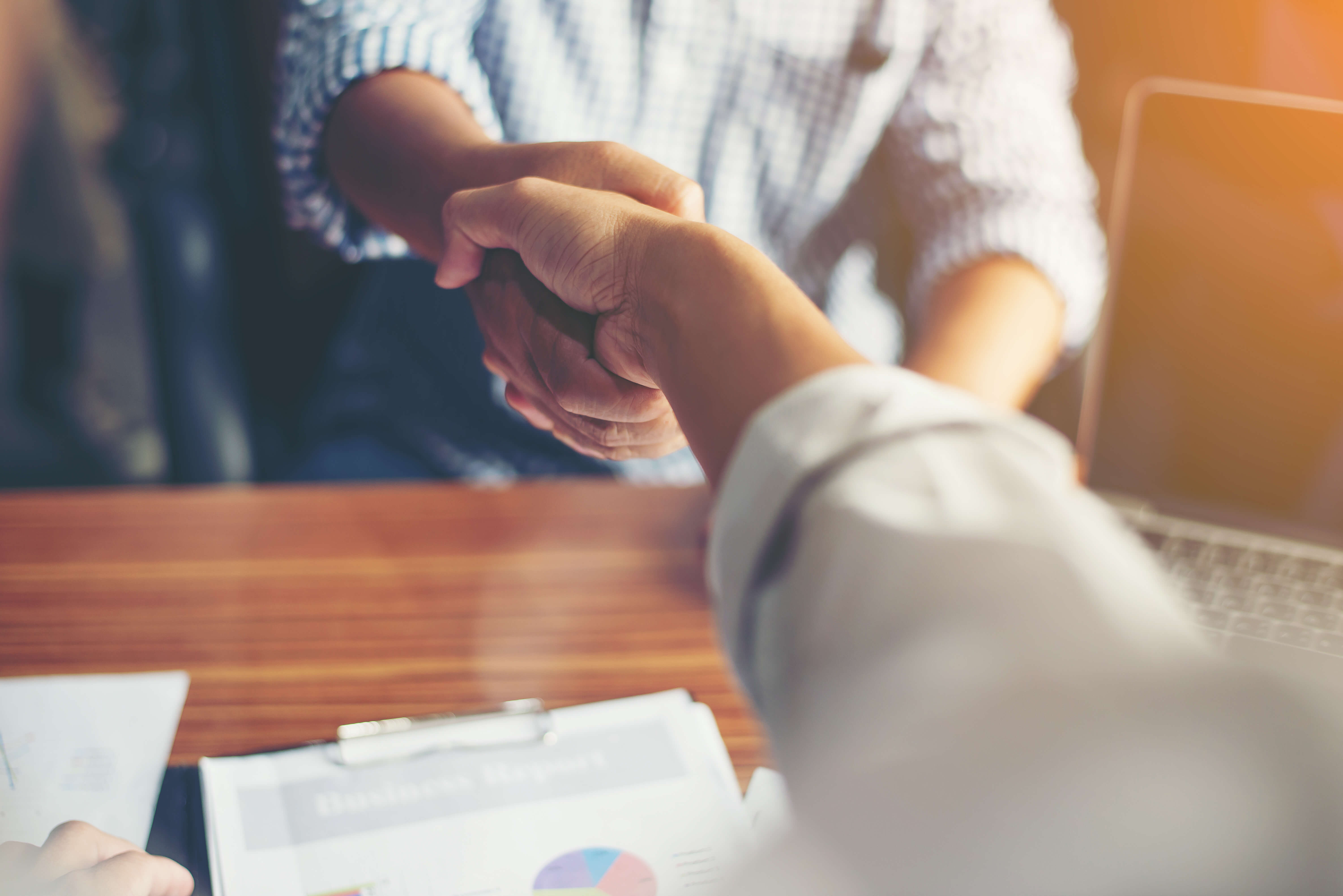 Handshake of two business people with a papers on the desk.